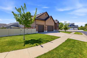Residence featuring a two-car garage, stucco and stone-veneer exterior, and a concrete driveway