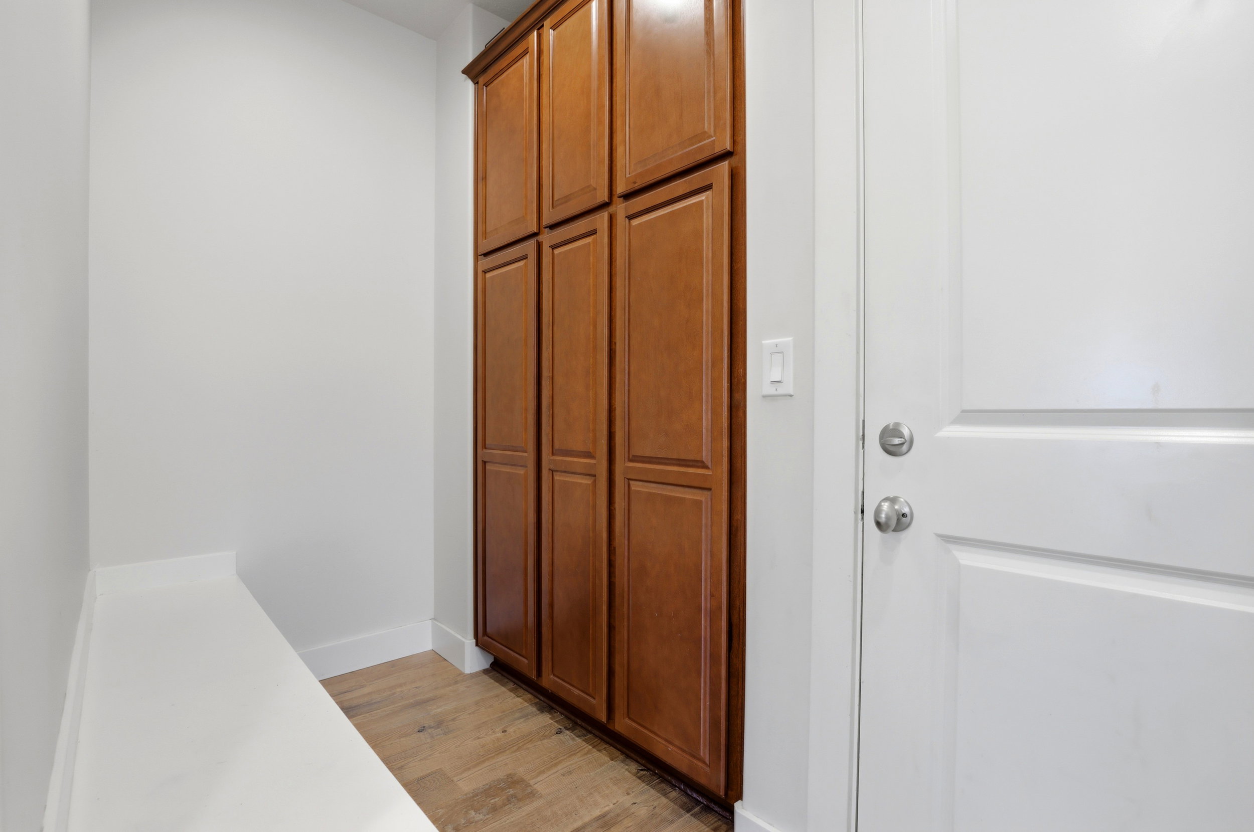 Entryway featuring a built-in bench, wood-finish flooring, and floor-to-ceiling cabinetry