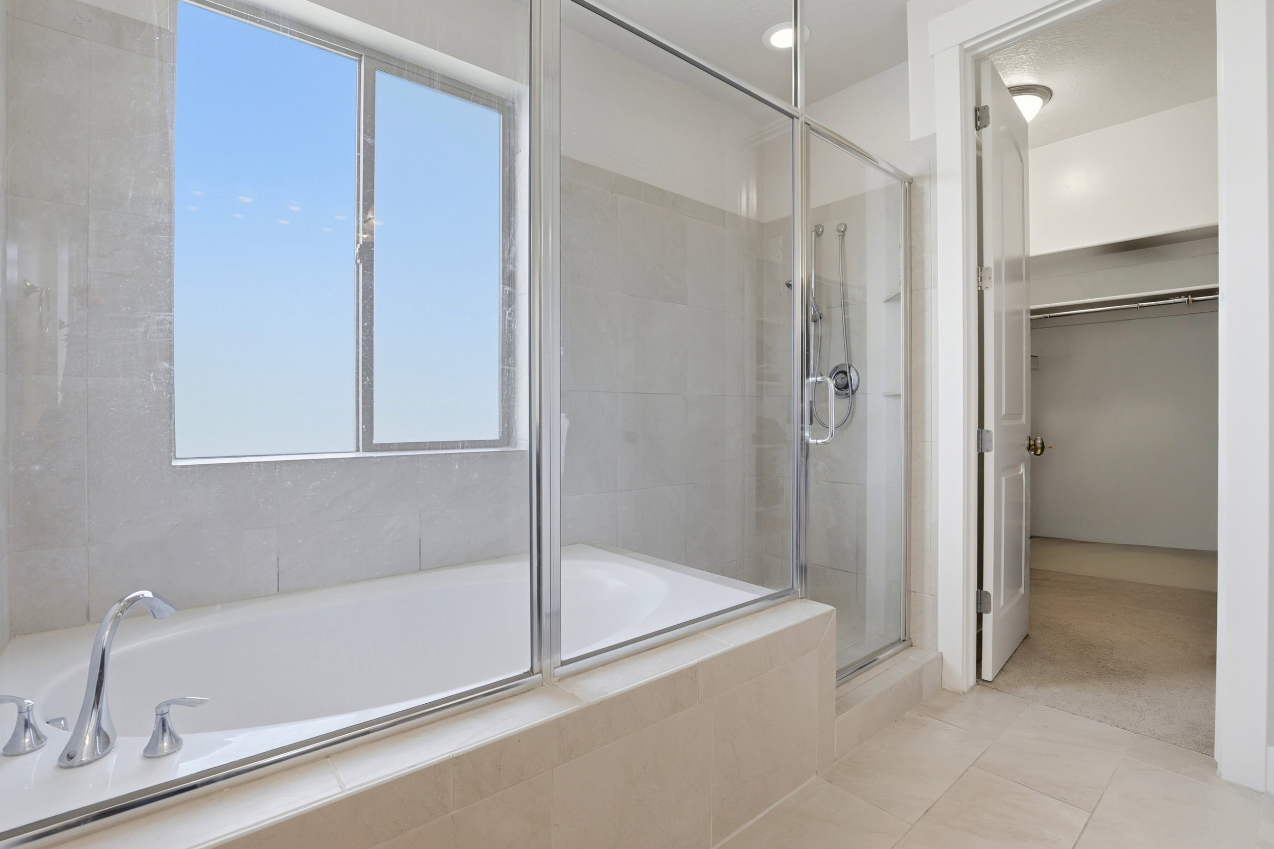 Bathroom featuring an integrated soaking tub and separate glass-enclosed shower with tiled surround