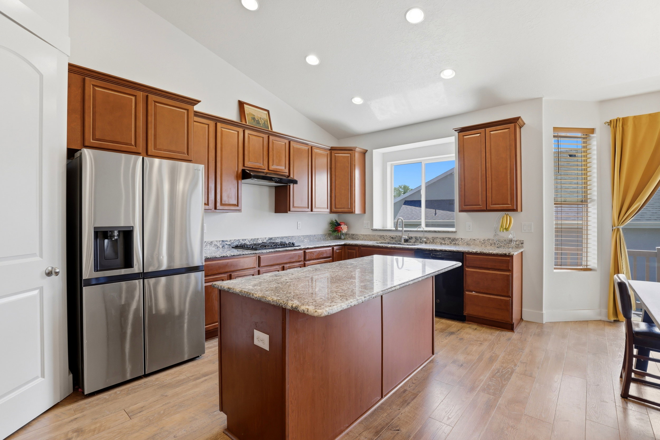 Open-concept kitchen featuring wood-finish flooring, recessed lighting, and a vaulted ceiling