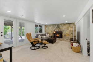 Spacious room featuring a stone accent wall with a built-in fireplace, recessed lighting, and light-colored carpeting