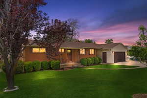 Brick-front ranch-style residence with an attached garage, a covered front porch, and a well-maintained lawn