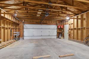 Spacious garage featuring exposed wood framing, an automatic overhead door, and concrete flooring