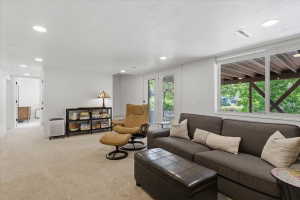 Carpeted living space featuring recessed lighting, a large window, and double glass doors