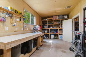 Utility space featuring a workbench with a light-colored surface, integrated wooden shelving, and a horizontal window