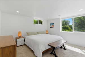 Spacious bedroom featuring recessed lighting, a large window with white framing, and wall-to-wall carpeting
