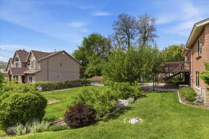 Expansive backyard featuring a lush lawn, mature landscaping, and a multi-level wooden deck with stairs