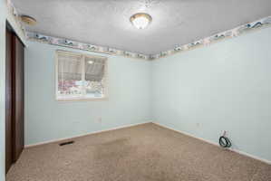 Carpeted room featuring light blue walls, a window with blinds, and a flush-mount ceiling light fixture