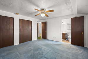 Room featuring blue carpeting, white walls, and a ceiling fan with light fixture