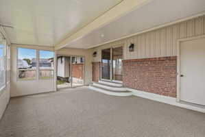 Covered patio featuring a durable textured floor and a full wall of windows