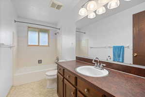 Bathroom featuring a wood-finish vanity with an integrated sink and chrome faucet, a full-width mirror, and overhead lighting