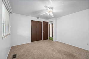 Spacious room featuring neutral carpet, white walls, a ceiling fan, and window blinds