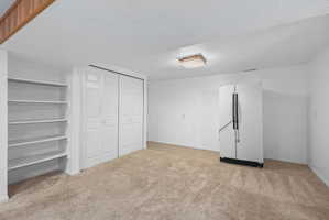 Carpeted room featuring built-in shelving, bi-fold closet doors, and a ceiling-mounted light fixture