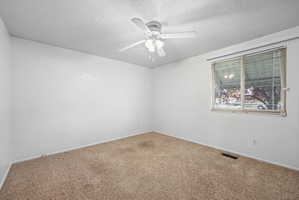 Light-filled room featuring neutral-toned carpet, a ceiling fan with integrated lighting, and a window with horizontal blinds