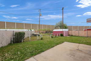 Expansive rear yard featuring green space, a concrete patio, and a red storage shed