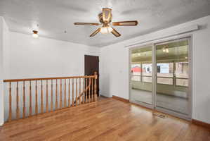 Open concept room featuring wood-finish flooring, a ceiling fan with integrated lighting, and a sliding glass door leading to an enclosed sunroom