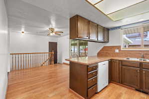 Kitchen featuring wood-finish flooring, wood cabinetry, a laminate countertop, and a double basin sink