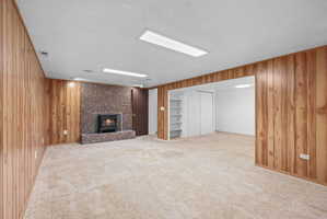 Spacious room featuring wood paneling, an exposed brick fireplace, and a wood-burning stove