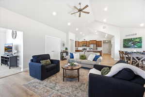 Living room with light wood finished floors, a ceiling fan, recessed lighting, and lofted ceiling