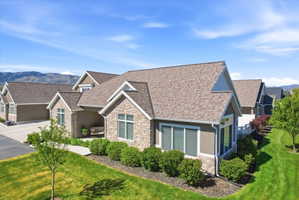 Craftsman-style home featuring stone siding, roof with shingles, a mountain view, a front yard, and stucco siding