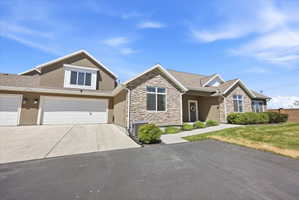 View of front of home featuring concrete driveway, an attached garage, stucco siding, and stone siding