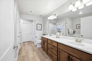Bathroom with double vanity, light wood-type flooring, and a shower stall