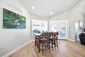 Dining area featuring lofted ceiling, light wood-style floors, french doors, and recessed lighting