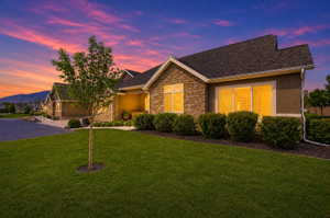 Ranch-style house featuring a front lawn, stone siding, stucco siding, and roof with shingles