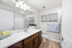 Full bath featuring vanity, curtained shower, and light wood-style flooring