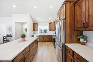 Kitchen featuring stainless steel appliances, wood finish cabinets, light wood-type flooring, a kitchen island, and recessed lighting