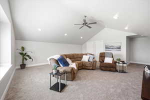Living room featuring light colored carpet and a ceiling fan