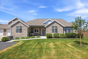 Craftsman-style home featuring stone siding, a front lawn, a porch, and roof with shingles