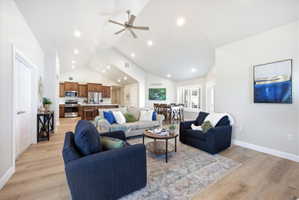Living area with a ceiling fan, light wood-type flooring, vaulted ceiling, and recessed lighting