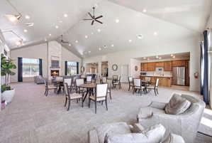 Dining space featuring a high ceiling, a fireplace, light colored carpet, and a ceiling fan