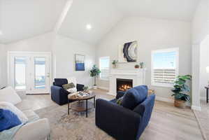 Living room with light wood-type flooring, a high ceiling, and a fireplace with flush hearth
