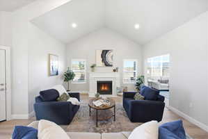 Living area with light wood-type flooring, a glass covered fireplace, and recessed lighting