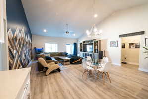 Open-concept living area featuring a vaulted ceiling and wood-finish flooring