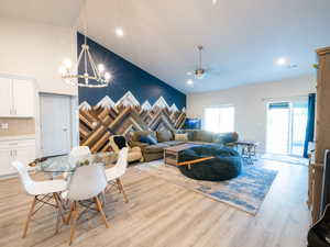 Vaulted ceiling great room featuring light wood-finish flooring, recessed lighting, and a unique wood accent wall