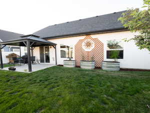 Expansive backyard featuring a concrete patio, covered gazebo with a tiered roof, and a sliding glass door entry