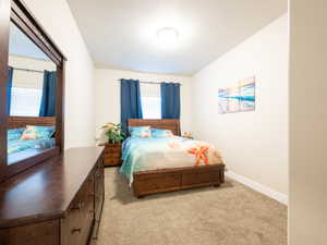 Bright sleeping space featuring neutral wall tones, textured carpeting, and a semi-flush mount ceiling light