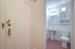 Bathroom featuring a pedestal sink, white toilet, recessed medicine cabinet, wall-mounted mirror, and an overhead vanity light fixture