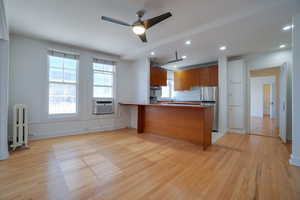 Open-concept living area featuring wood-finish flooring, a contemporary ceiling fan, and recessed lighting