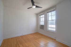 Room with wood-finish flooring, white baseboards, and two windows