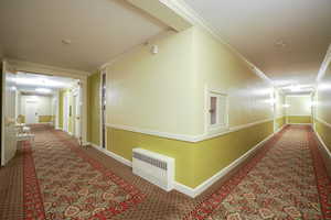 Corridor featuring patterned carpeting, two-tone wall treatment, white crown molding, and recessed lighting