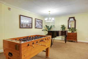 Carpeted room featuring crown molding and a contemporary chandelier