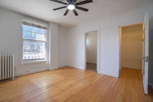 Spacious room featuring wood-finish flooring and white walls