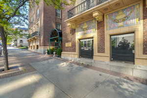 Historic brick facade featuring decorative architectural elements, ornate balcony railings, a distinctive arched entryway, and large storefront windows