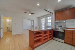 Kitchen area featuring wood-finish cabinetry, stainless steel range, and tile flooring
