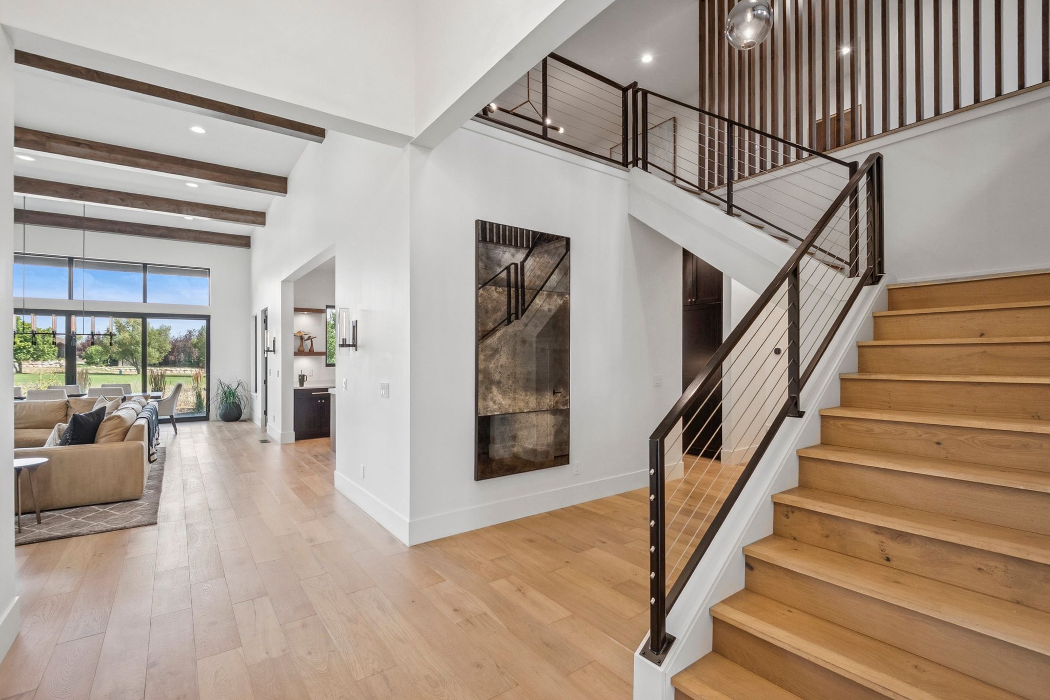 Two-story entry featuring a contemporary staircase with metal railings, double-height ceiling, and designer details.