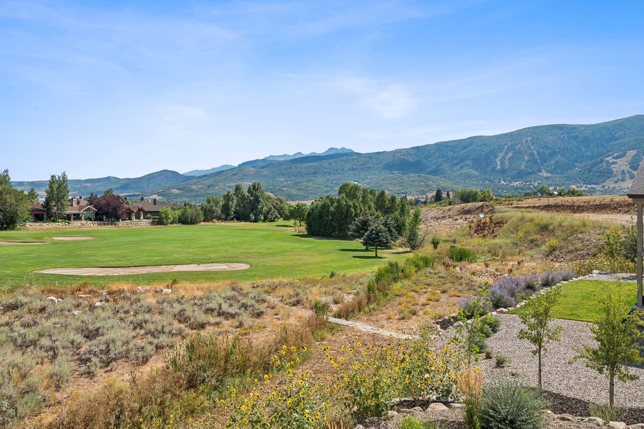 Expansive green space featuring a golf course, mountain backdrop, and distant ski slopes
